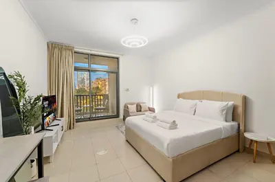 a bedroom with a large white bed and a television at Cozy Studio with Scenic Canal Views in Dubai
