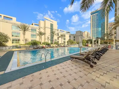 a swimming pool in a resort with chairs and buildings at Cozy Studio with Scenic Canal Views in Dubai