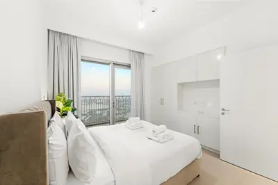 a white bedroom with a white bed and a window at Elegant 2BR in Downtown Dubai l Walk to Dubai Mall in Dubai