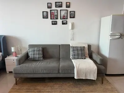 a living room with a gray couch and pictures on the wall at Cozy Studio- Dubai Marina in Dubai