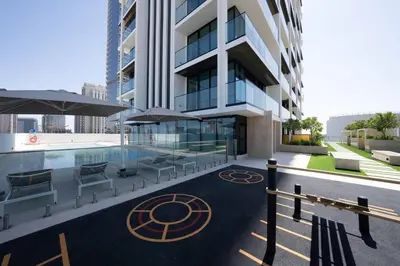 a building with a pool and some chairs and umbrellas at Modern & Elegant 1br Apartment In Jvc in Dubai