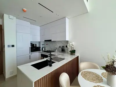 a kitchen with white cabinets and a table with chairs at Chic Urban 1br In Jvc With Modern Amenities in Dubai