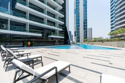 a swimming pool in a building with chairs and a building at Luxury Living , Beautiful Layout in Dubai