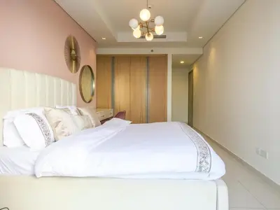 a bedroom with a large white bed with a chandelier at High Floor , Premium 1 Bedroom , Stunning Views in Dubai