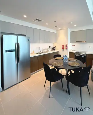 a kitchen with a table with chairs and a refrigerator at 2BR Forte Tower 1 Downtown 3mn Burj Khalifa in Dubai