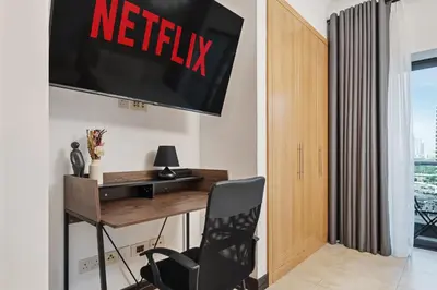 a office with a desk and a television on the wall at Chic Studio in Goldcrest Views, JLT in Dubai