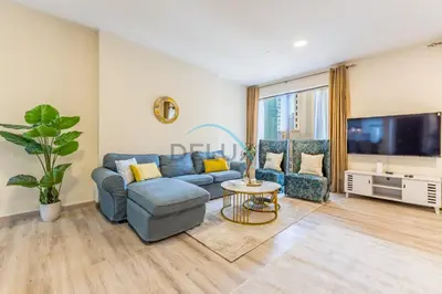 a living room with a blue couch and a tv at Lovely Studio in Murjan 2, Jumeirah Beach Residence by Deluxe Holiday Homes in Dubai