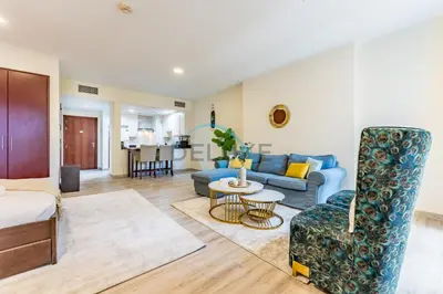 a living room with a blue couch and a table at Lovely Studio in Murjan 2, Jumeirah Beach Residence by Deluxe Holiday Homes in Dubai