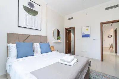 a bedroom with a large white bed with blue pillows at Heaven Crest Vacation Homes Downtown - 3 Bedroom Suites 2 minute walk to Dubai Mall and Burj Khalifa in Dubai