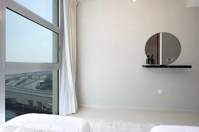 a white bedroom with a mirror and a window at Cozy Urban 2BR Apartment in DEC Tower Marina in Dubai