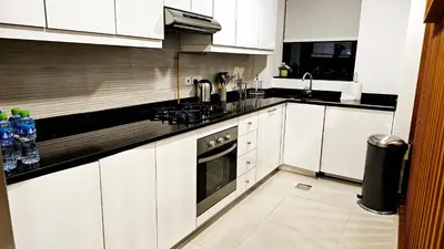 a white kitchen with a sink and a stove at Elegant 2-Bedroom Apartment with Private Balconies & En-Suite Luxury in Meydan Avenue in Dubai
