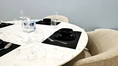 a white marble table with glasses and plates on it at Elegant 2-Bedroom Apartment with Private Balconies & En-Suite Luxury in Meydan Avenue in Dubai