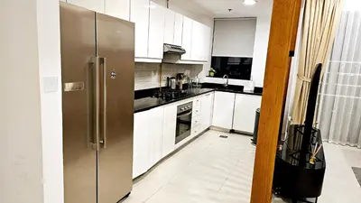 a kitchen with white cabinets and a stainless steel refrigerator at Elegant 2-Bedroom Apartment with Private Balconies & En-Suite Luxury in Meydan Avenue in Dubai