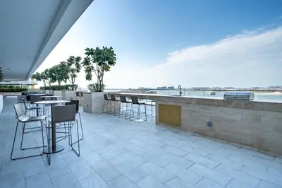 a patio with tables and chairs and a view of the water at Homes Beyond l Elegant 2BR with Wide Sea Views in Dubai