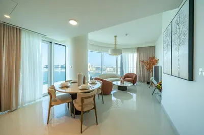 a living room with a table and chairs and a couch at Homes Beyond l 2BR Panoramic Skyline & Sea View in Dubai