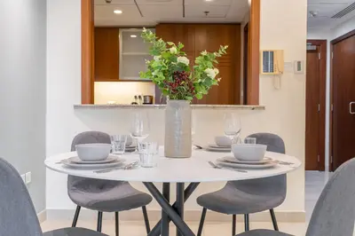 a white table with chairs and a vase with flowers at Sophisticated and Elegant 2BR in Downntown Dubai in Dubai