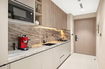 a kitchen with white cabinets and a red appliance at FIRST CLASS Studio Stylish Living in Dubai