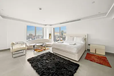 a white bedroom with a bed and a large window at Elegant 2BR with Burj Views, Pool, Gym, and Quick Metro Access in Dubai