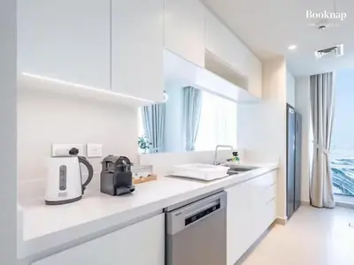 a white kitchen with a coffee maker on a counter at Lavish 3BR Apartment with Assistant Room in Habour Gate Tower in Dubai
