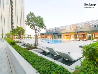 a swimming pool with lounge chairs in a building at Lavish 3BR Apartment with Assistant Room in Habour Gate Tower in Dubai