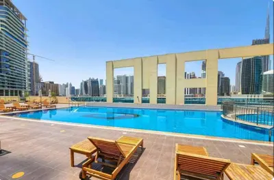a large swimming pool with chairs and a building at April OFFER Huge 1BKH 4people & high floor in Dubai