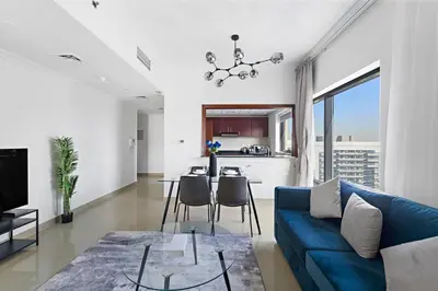 a living room with a blue couch and a table at Time Place Near Metro and Mall in Dubai