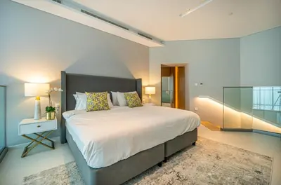 a bedroom with a large bed and a glass wall at Iconic 1Bedroom Duplex with Skyline Views Near Downtown Dubai & Burj Khalifa in Dubai