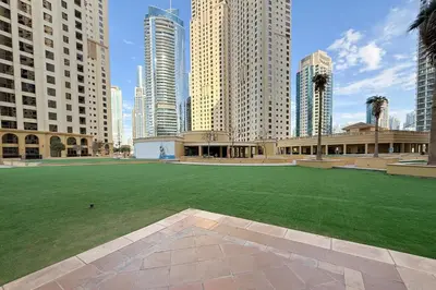 a large green field in a city with tall buildings at Beachside Home on JBR Walk with modern interiors in Dubai
