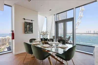 a dining room with a glass table and green chairs at Livbnb - Ain Dubai Panorama, 3BR with Maid's Room in Dubai