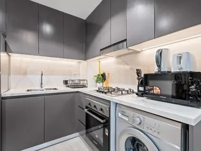 a kitchen with a sink and a washer and dryer at Cozy Stay 1BR in Azizi Pearl in Dubai