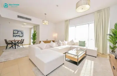 a living room with a white couch and a table at Blue Breeze - Elegant 3BR Apt with Panoramic Marina Views in JBR in Dubai
