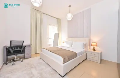 a bedroom with a bed and a desk and a chair at Blue Breeze - Elegant 3BR Apt with Panoramic Marina Views in JBR in Dubai
