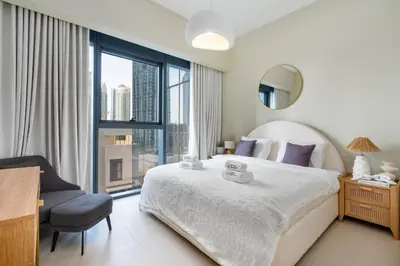 a bedroom with a bed and a chair and a large window at BLVD - Steps from Dubai mall and Dancing Fountain in Dubai