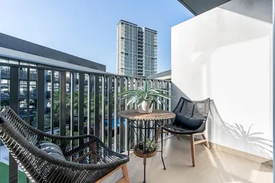 a balcony with chairs and a table with a plant at Stylish 1BR APT with Gym, Pool & Private Parking in Dubai