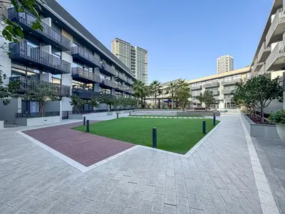 a courtyard in an apartment building with a grass field at Stylish 1BR APT with Gym, Pool & Private Parking in Dubai