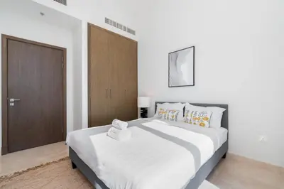 a bedroom with a large white bed and a wooden door at Holiday Boulevard - Luxury 3BR Penthouse with Burj Khalifa and Creek Views in Dubai