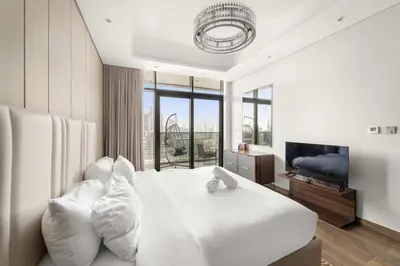 a bedroom with a white bed with pillows and a television at Elegant 1BR with Panoramic Views on Burj Khalifa in Dubai
