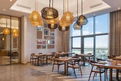 a restaurant with tables and chairs and large windows at Sky-High 2BR - Infinity Pool & Burj Khalifa Views in Dubai