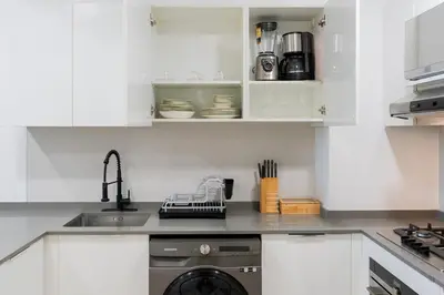 a white kitchen with a sink and a dishwasher at Spacious l Opened View l Fits 4 in Dubai