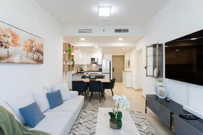 a living room with a white couch and a kitchen at Spacious l Opened View l Fits 4 in Dubai