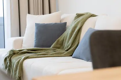 a blanket sitting on a white couch with pillows at Spacious l Opened View l Fits 4 in Dubai