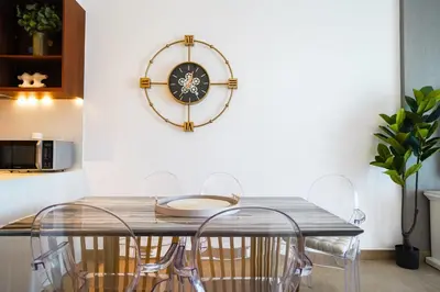 a dining room table with chairs and a clock on the wall at Sea View l Port De LaMer l Next to Beach l Perfect for 4 in Dubai