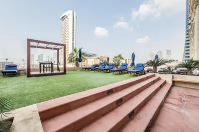 a rooftop patio with chairs and a table and grass at Remodeled 1BR with Sky-High Picturesque Marina Views, Elite Residence, Dubai Marina by Deluxe Holiday Homes in Dubai