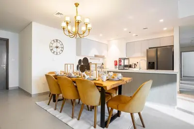 a kitchen and dining room with a wooden table and chairs at FIRST CLASS 3BR Burj Khalifa & Fountain view in Dubai