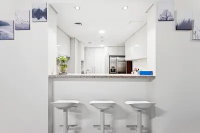 a kitchen with white counters and stools at 3BR Family abode with Iconic Burj Khalifa view in Dubai