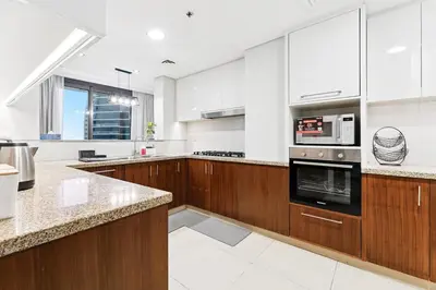 a large kitchen with white walls and wooden cabinets at 3BR Family abode with Iconic Burj Khalifa view in Dubai