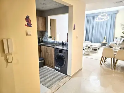 a kitchen and living room with a washer and dryer at Deluxe 1BHK Apt in JVC, Self check in ! in Dubai