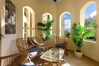 a porch with chairs and a table and windows at Spacious 2BR with Pool & Private Beach Access in Dubai