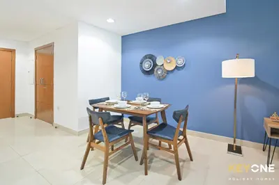 a dining room with a table and chairs and a blue wall at Fascinating Ocean Views in a One Bedroom in Dubai