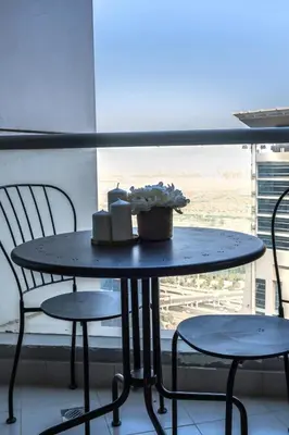 a table with two chairs and a basket of flowers on it at Marina Majesty- Homely & Cozy 2BR, CanalView, Central Location in Dubai